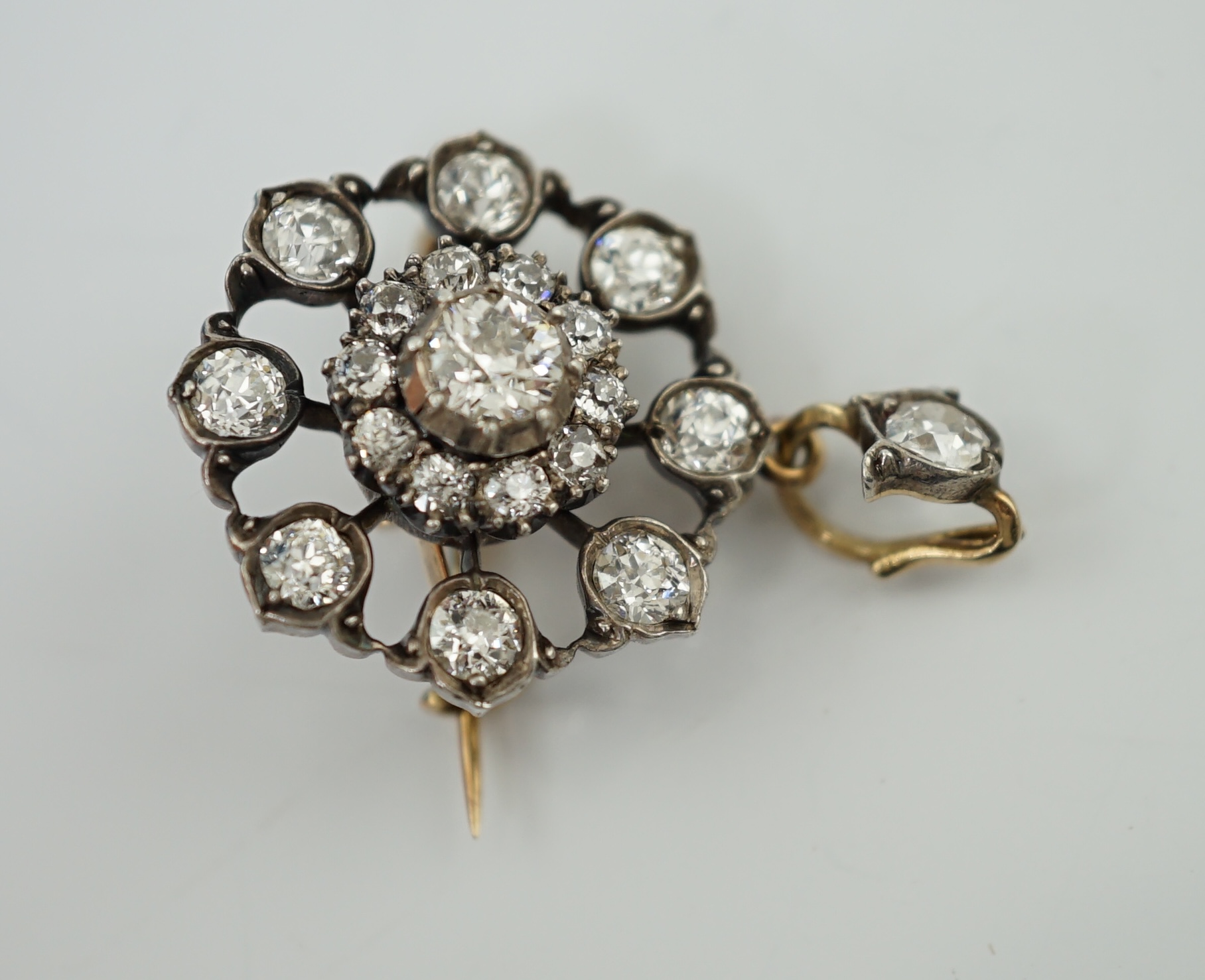 An early 20th century gold and silver mounted diamond cluster set circular pendant brooch